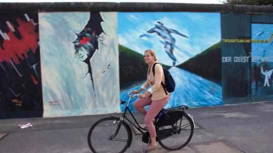 Sanne Boersma fietst langs de East Side Gallery